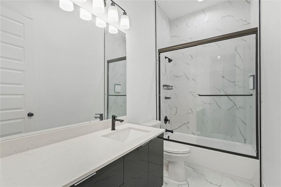 Full bath with marble finish floors, vanity, and bath / shower combo with glass door