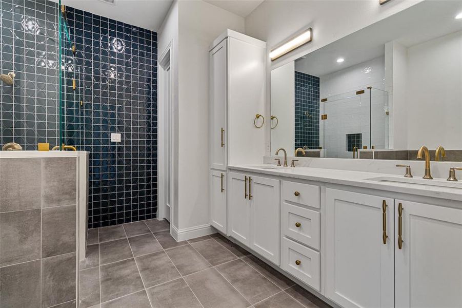 Bathroom featuring vanity, a tile shower, tile walls, and tile patterned flooring