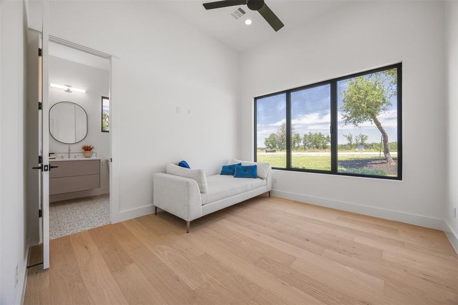 Downstairs guest bedroom #1 A well-lit interior features wide-plank wood flooring and a panoramic view of the outdoors.