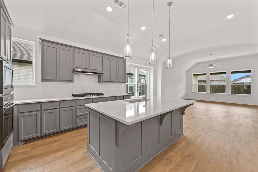 Kitchen featuring gray cabinets, lofted ceiling, visible vents, and a sink