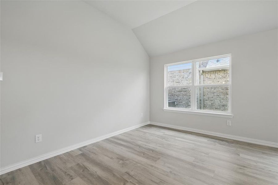 Empty room with light wood-type flooring, baseboards, and lofted ceiling Empty room with light wood-type flooring, baseboards, and lofted ceiling