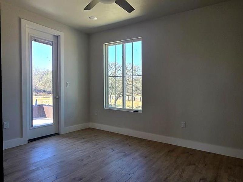 Empty room featuring healthy amount of natural light, wood finished floors, and a ceiling fan