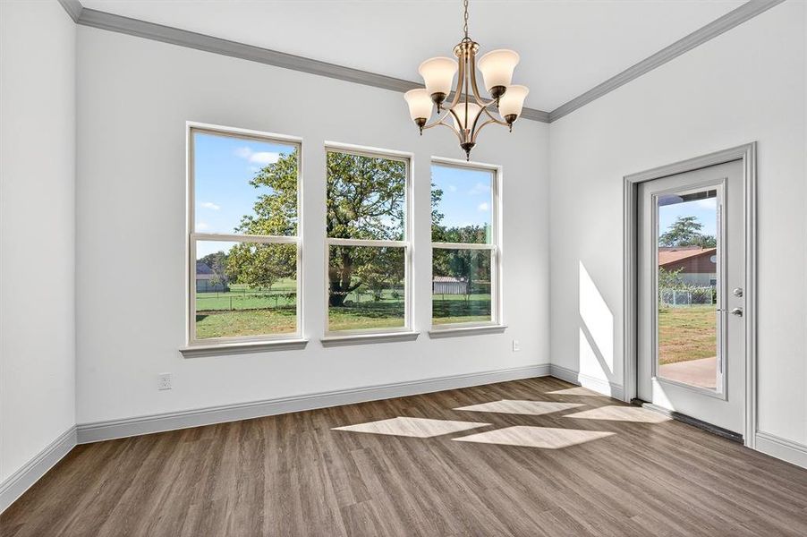 Unfurnished dining area featuring wood finished floors, ornamental molding, and a chandelier