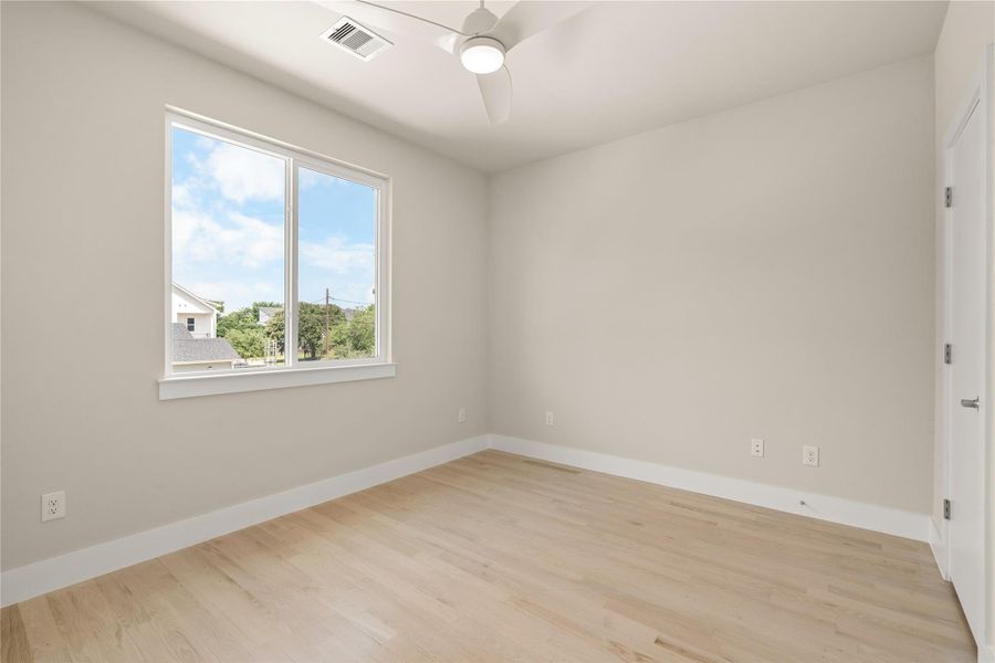 Secondary bedroom with tall windows, ceiling fan and clean architectural lines.