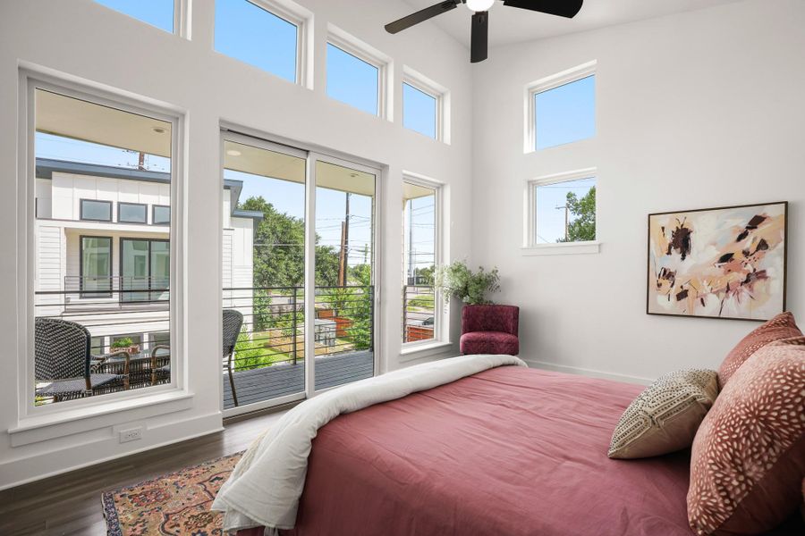 Natural light floods this primary bedroom through tall windows and a sliding glass door opening to a private balcony. Natural light floods this primary bedroom through tall windows and a sliding glass door opening to a private balcony.