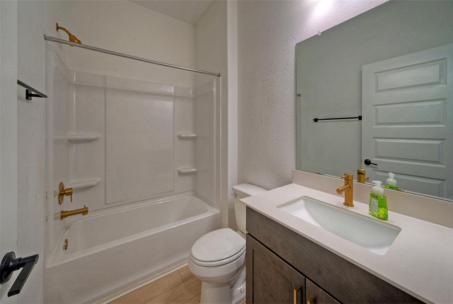 Gold hardware adds a modern touch to the clean tub and vanity combination. Gold hardware adds a modern touch to the clean tub and vanity combination.