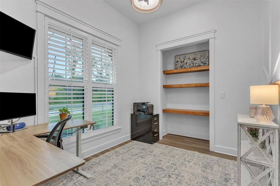 Office area featuring wood-type flooring, plantation shutters and wood accented floating shelves. Could also be a 4th bedroom. Office area featuring wood-type flooring, plantation shutters and wood accented floating shelves. Could also be a 4th bedroom.
