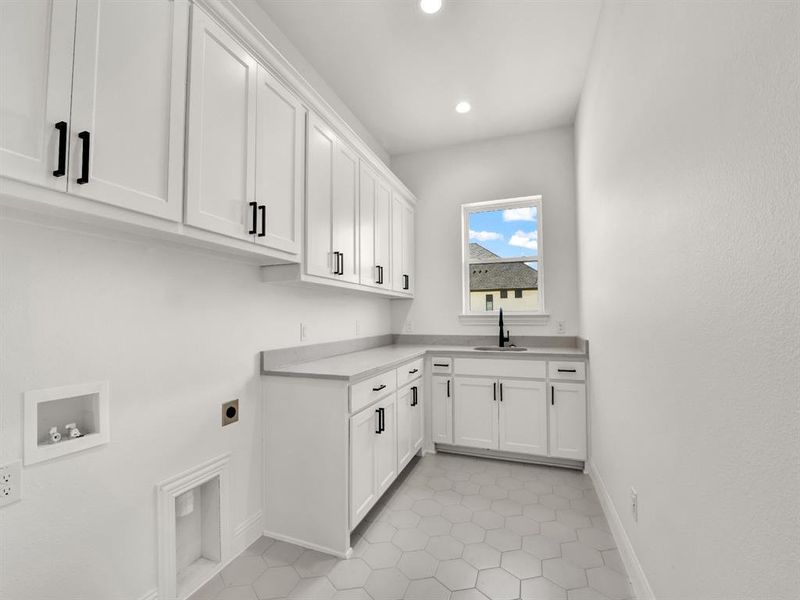 Laundry area featuring hookup for a washing machine, hookup for an electric dryer, a sink, baseboards, and cabinet space Laundry area featuring hookup for a washing machine, hookup for an electric dryer, a sink, baseboards, and cabinet space