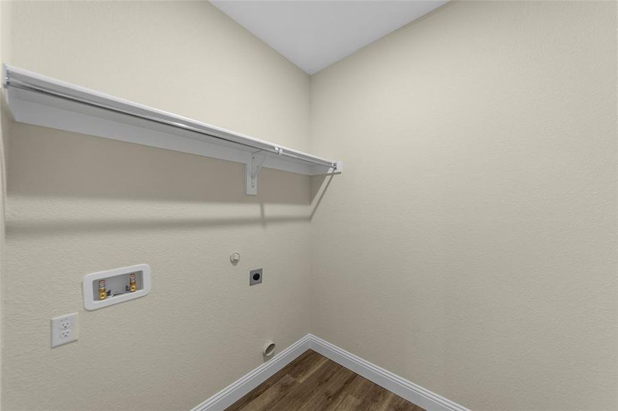 Dedicated utility space featuring wood-finish flooring, light neutral walls, and white baseboards
