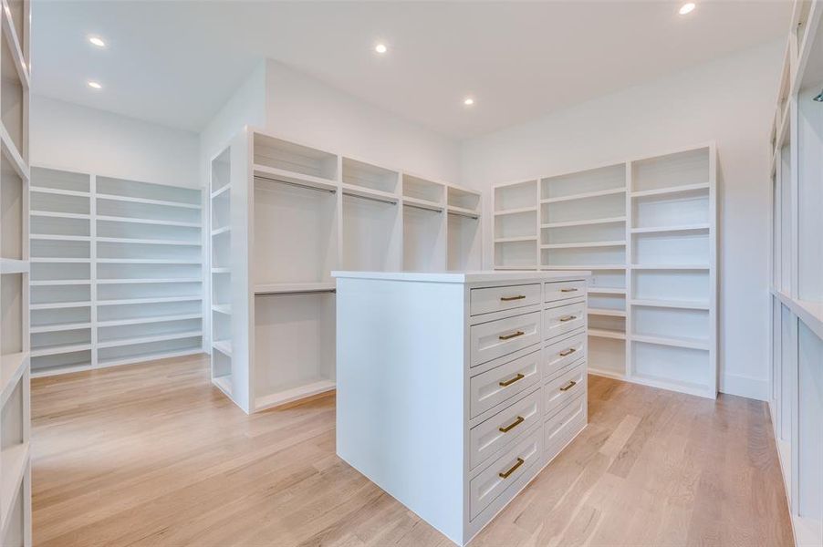 Walk in closet with light hardwood / wood-style flooring