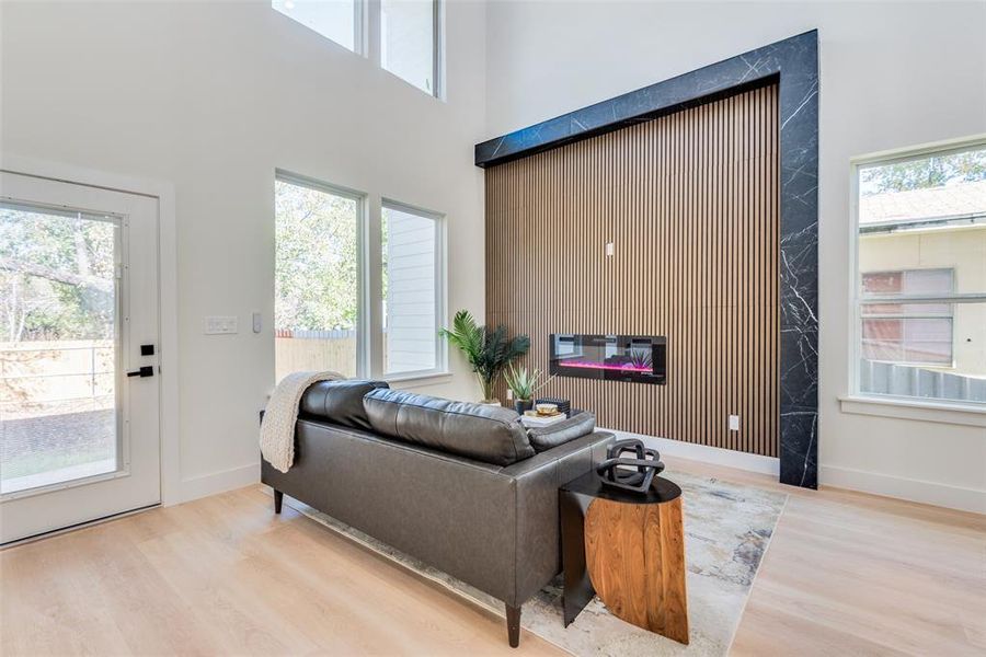 Living room featuring plenty of natural light, a towering ceiling, and light wood-type flooring