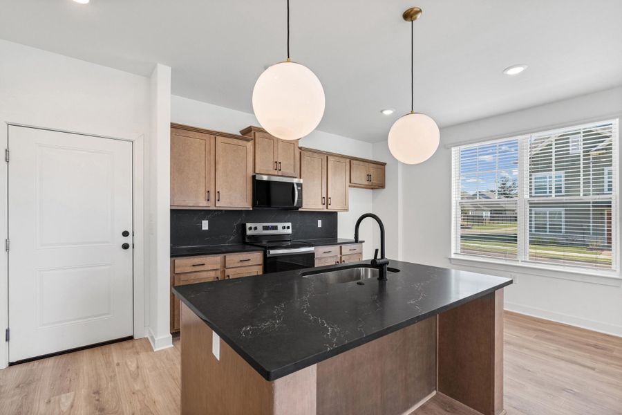 Kitchen featuring a central island with a sink, wood-finish flooring, light wood cabinetry, and recessed lighting
