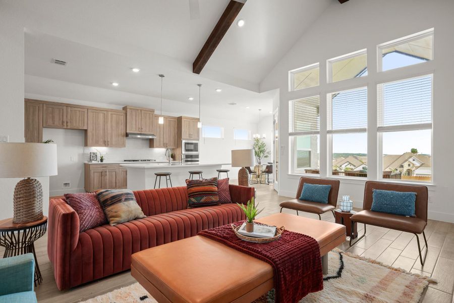 A spacious great room showcasing vaulted ceilings, modern kitchen integration, and abundant natural light.
