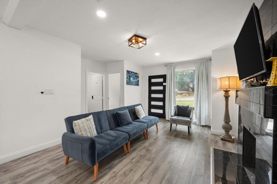 Living room featuring light wood-type flooring, recessed lighting, and a tile fireplace Living room featuring light wood-type flooring, recessed lighting, and a tile fireplace