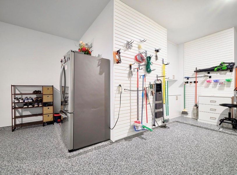 Expansive garage with sleek epoxy flooring, tool wall, and ample storage shelves—ideal for parking and organization.
