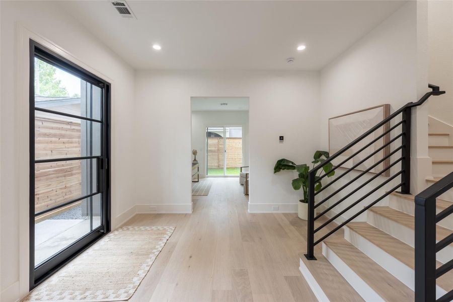 Houston light, properly framed. Morning sun filters through the cedar side courtyard, crosses the oak floors, and lands at the far glass wall of the rear study; a corridor of daylight that moves with the hour. A home designed around its exposure, not despite it.