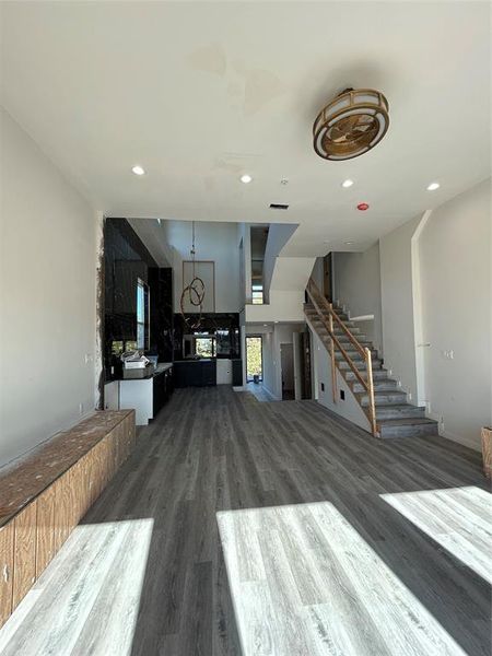 Unfurnished living room featuring dark wood-style flooring, stairs, and recessed lighting