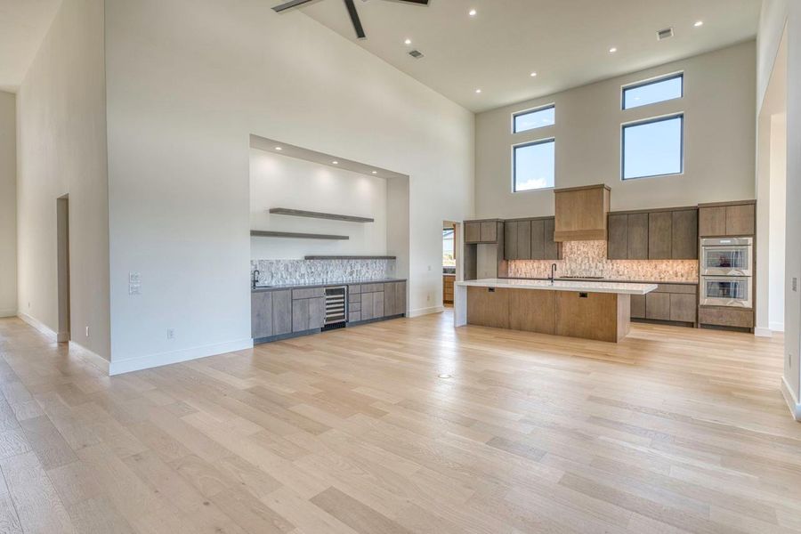 High ceilings and modern wood flooring anchor this open-concept kitchen and wet bar area.
