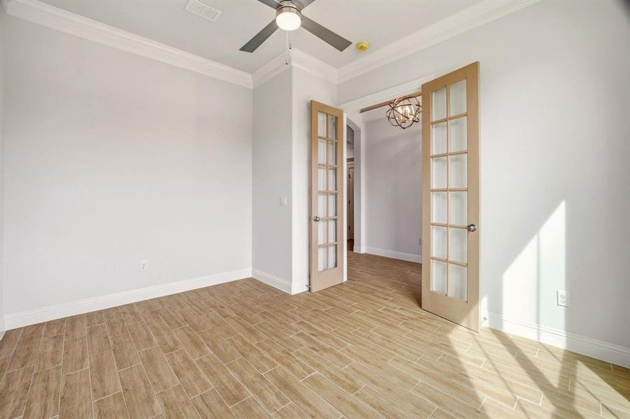 Spare room featuring french doors, crown molding, wood finish floors, and a ceiling fan Spare room featuring french doors, crown molding, wood finish floors, and a ceiling fan