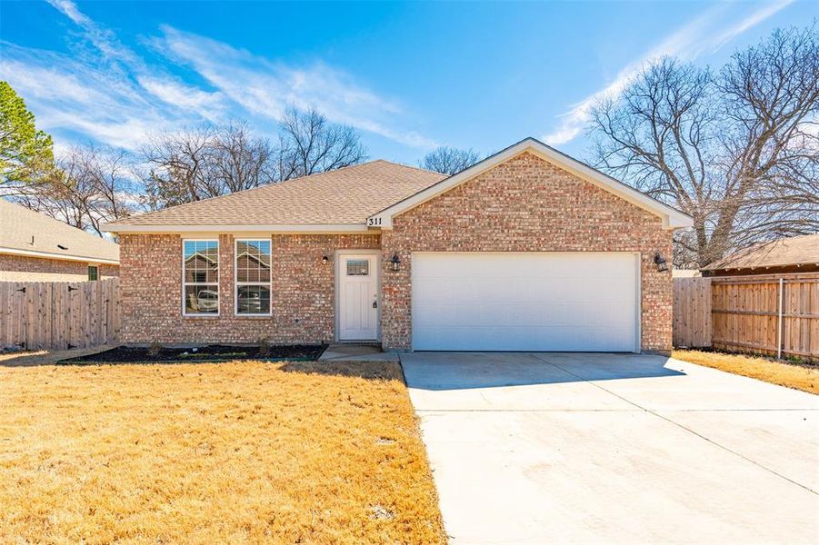 Single story home featuring a garage, fence, concrete driveway, and brick siding