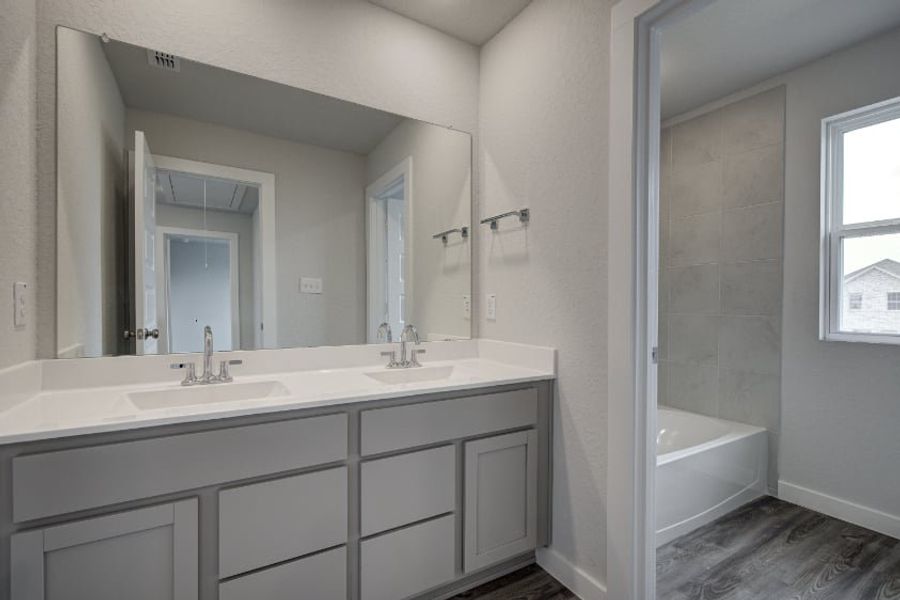 A bathroom with a tub sink and mirror. A bathroom with a tub sink and mirror.