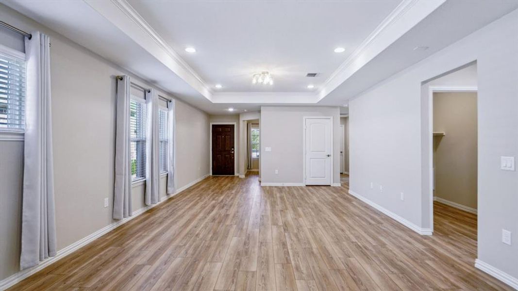 Empty room featuring light wood-type flooring, a raised ceiling, crown molding, and recessed lighting Empty room featuring light wood-type flooring, a raised ceiling, crown molding, and recessed lighting