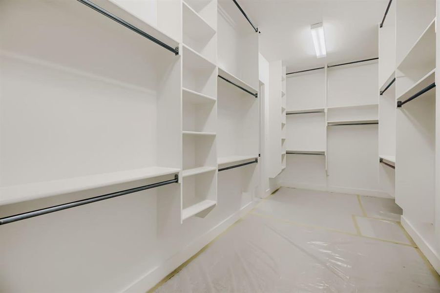 Walk-in closet featuring extensive built-in shelving, multiple hanging rods, and recessed overhead lighting Walk-in closet featuring extensive built-in shelving, multiple hanging rods, and recessed overhead lighting