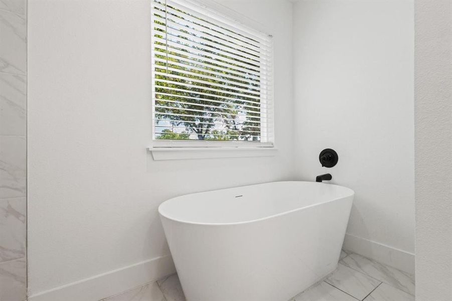 Bathroom featuring a freestanding tub and marble look tile flooring