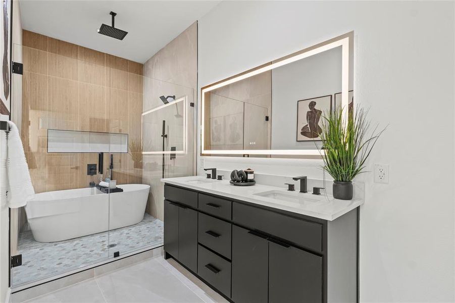 Full bath featuring a freestanding tub, double vanity, a tile shower, and light tile patterned floors