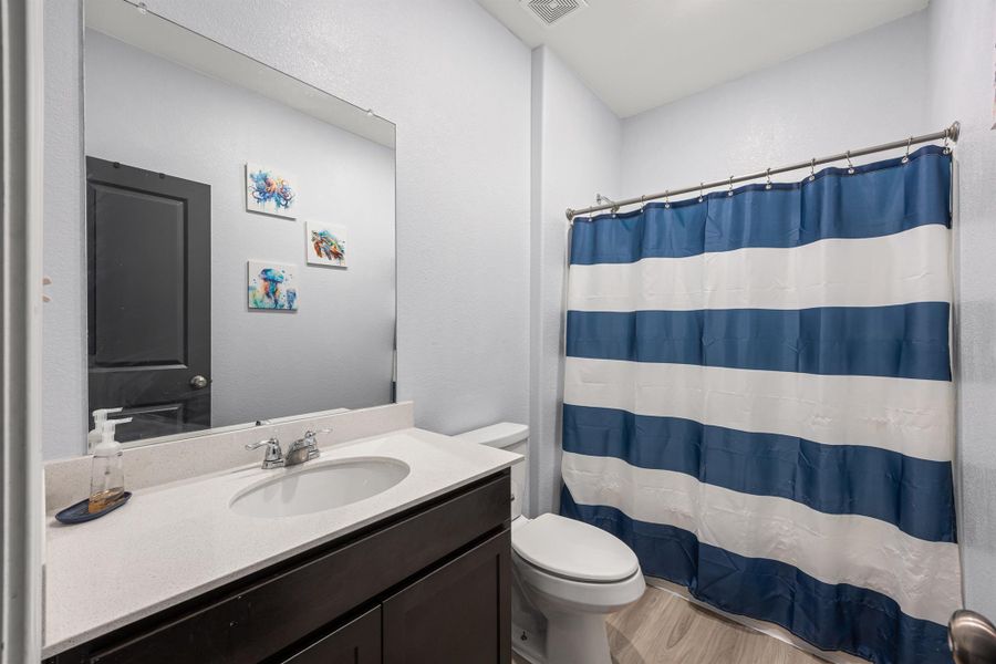 Bathroom featuring vanity, LVP floors, and a bathtub with a shower curtain Bathroom featuring vanity, LVP floors, and a bathtub with a shower curtain