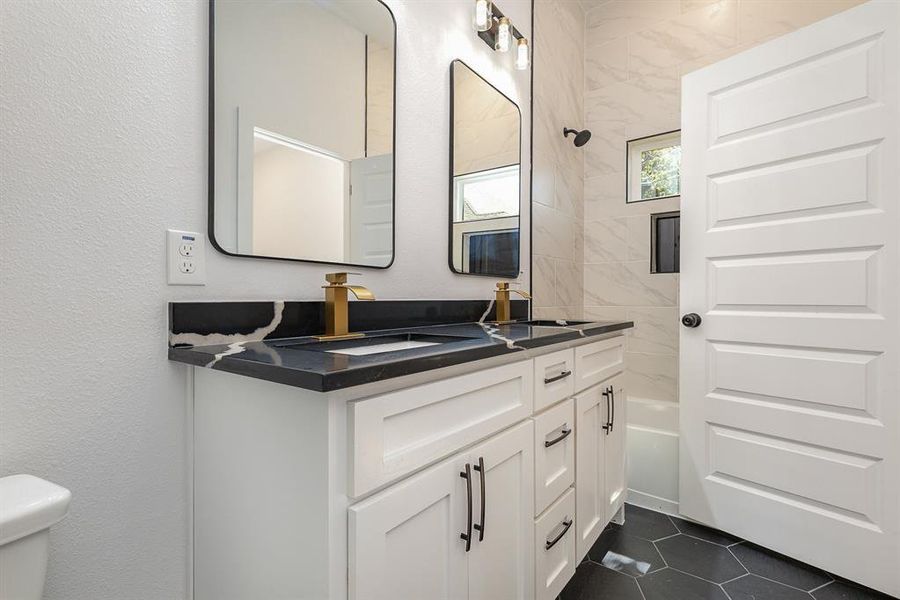 Bathroom with a sink, toilet, double vanity, shower / bath combination, and tile patterned flooring