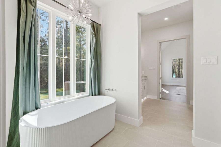 A spa-level escape featuring asculptural freestanding soakingtub set beneath oversizedpicture windows, dramaticstatement chandelier, and aserene view that turns everydayroutines into a luxury experience.
