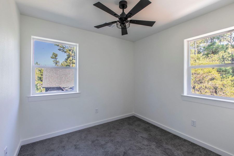 Unfurnished room featuring dark carpet and ceiling fan