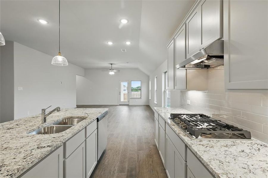 Kitchen featuring dark wood-type flooring, appliances with stainless steel finishes, under cabinet range hood, light stone counters, and a ceiling fan Kitchen featuring dark wood-type flooring, appliances with stainless steel finishes, under cabinet range hood, light stone counters, and a ceiling fan