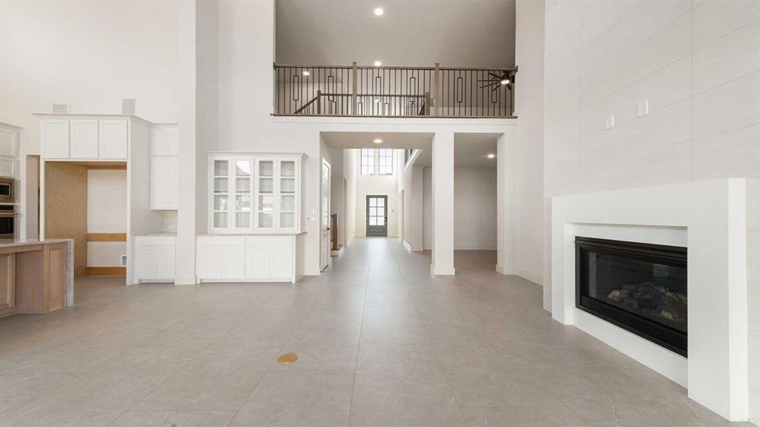 Unfurnished living room with ceiling fan, light tile patterned floors, and a high ceiling