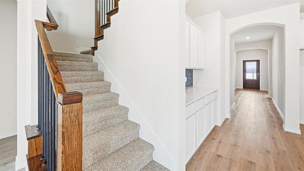 Staircase with wood finished floors, arched walkways, and recessed lighting