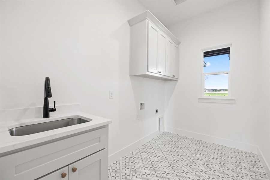 Washroom with electric dryer hookup, baseboards, a sink, and cabinet space