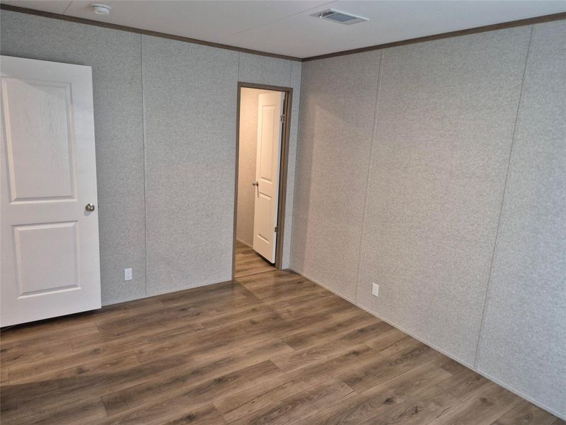 Unfurnished bedroom with dark wood finished floors, ornamental molding, and a decorative wall