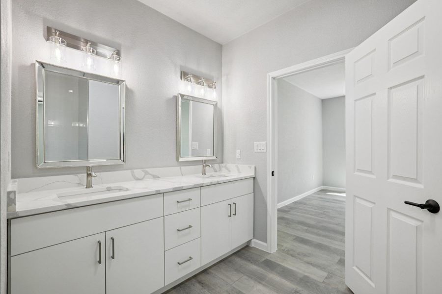 Full bath featuring double vanity and light wood-type laminate flooring