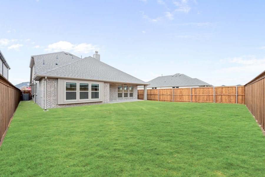 Backyard with large green lawn, brick home exterior, and tall wood privacy fence on both sides Backyard with large green lawn, brick home exterior, and tall wood privacy fence on both sides