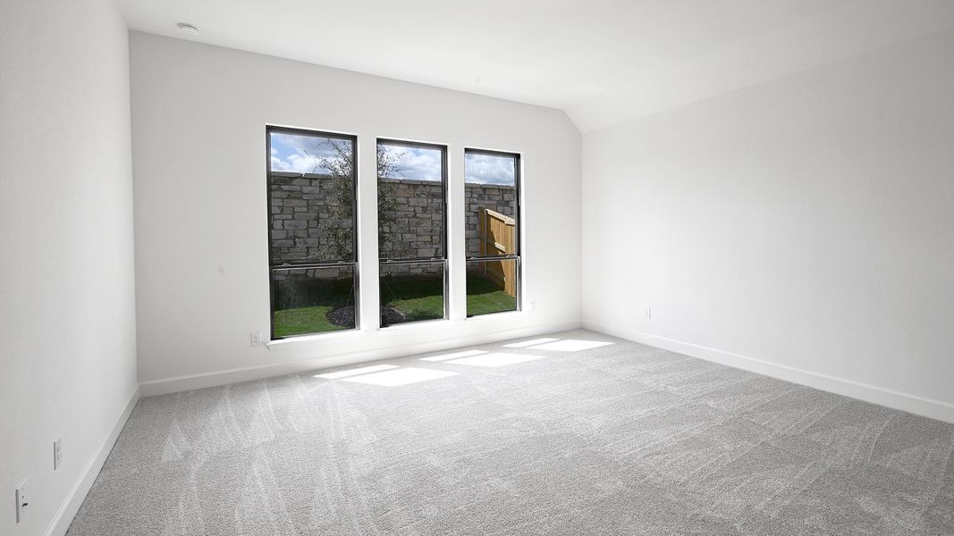 Carpeted empty room with baseboards and lofted ceiling Carpeted empty room with baseboards and lofted ceiling
