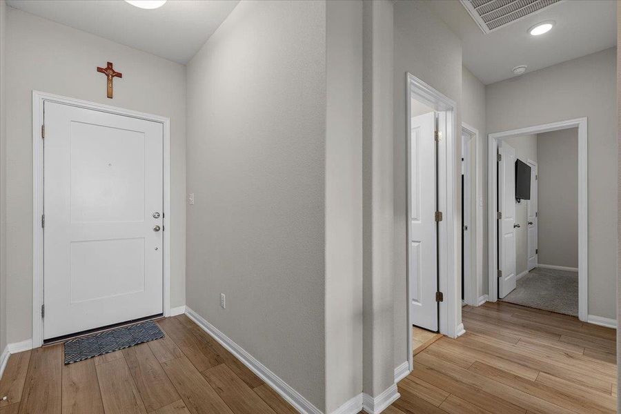 Warm wood flooring and clean white moldings define this welcoming entry hallway.