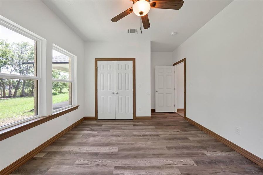 Unfurnished bedroom featuring wood finished floors, a closet, and a ceiling fan