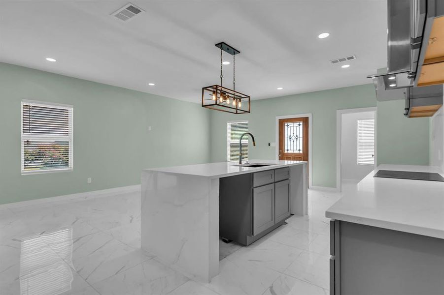 Kitchen featuring light marble finish flooring, light stone counters, plenty of natural light, recessed lighting, and range hood Kitchen featuring light marble finish flooring, light stone counters, plenty of natural light, recessed lighting, and range hood