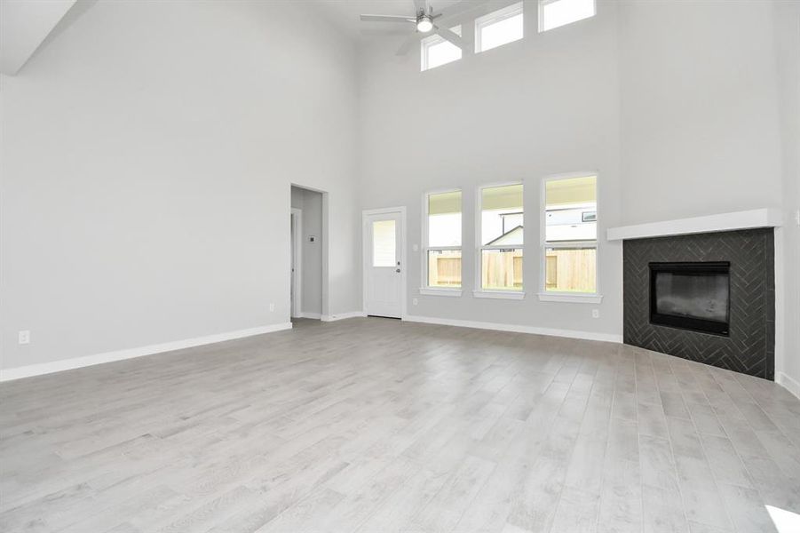 Family room flooded with natural light through the expansive windows.  The premium tile flooring adds a touch of luxury to the space, creating the perfect setting for relaxing moments and cherished gatherings with loved ones.  Sample photo of completed home with similar plan. As built color and selections may vary.