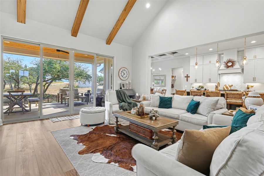 Living room featuring high vaulted ceiling, LVP flooring, with sliding glass doors to back patio and open to kitchen & dining area