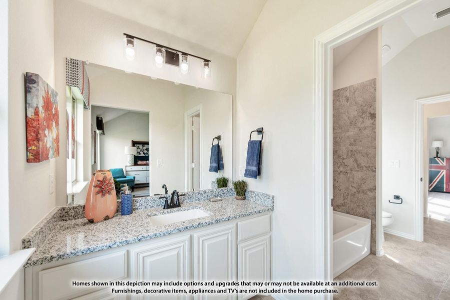 Bathroom with white cabinets, granite countertop, large mirror, and soaking tub with tile surround visible in background.