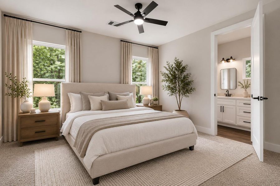 This photo shows a bright bedroom with soft carpeting, two windows offering natural light, and an attached bathroom featuring modern fixtures and ample cabinet space.