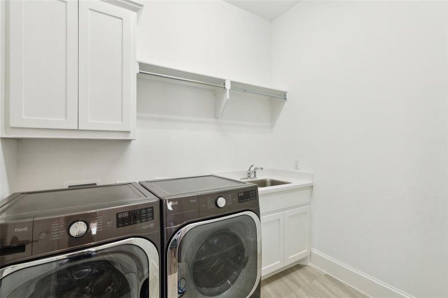 Laundry room with sink, independent washer and dryer, light hardwood / wood-style floors, and cabinets