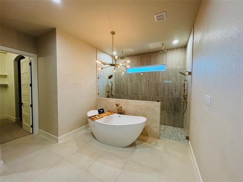 Bathroom with a notable chandelier, shower with separate bathtub, and tile patterned floors